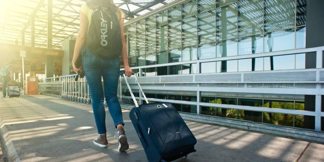 Mujer camina con una maleta hacia el aeropuerto para comenzar un viaje